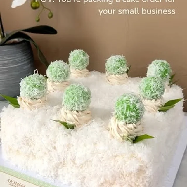 A klepon cake being boxed with a birthday topper