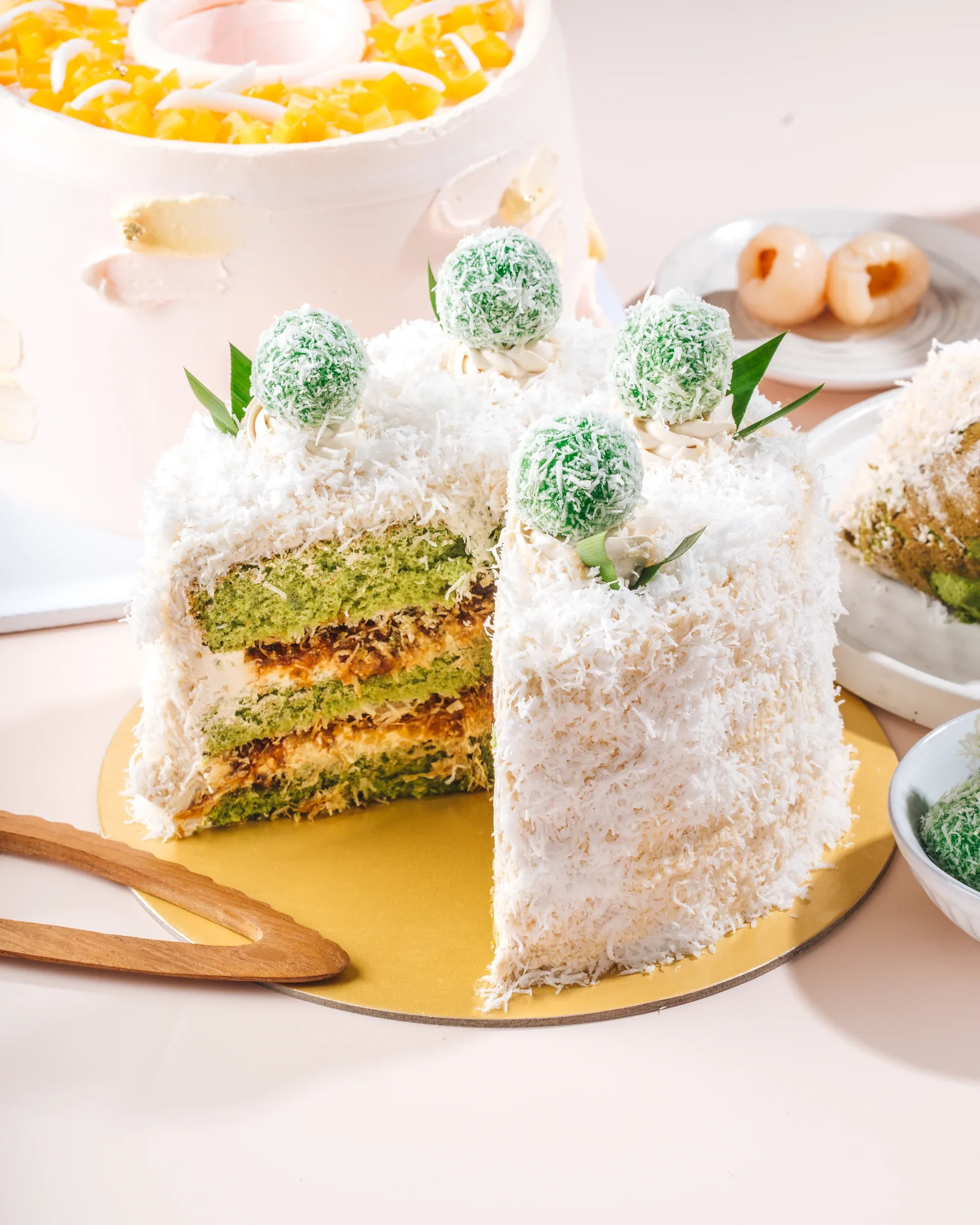 A cut slice of Momma Jakarta klepon cake showing its pandan sponge layers, gula melaka and coconut